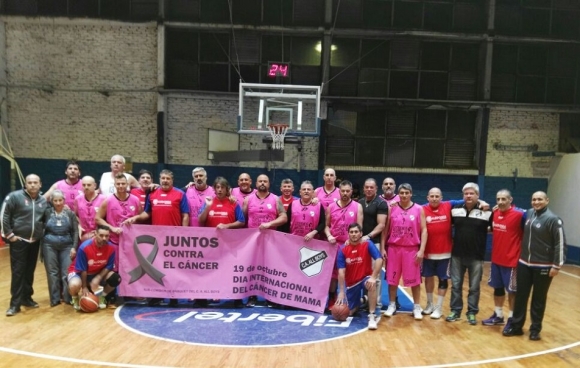 Los dos equipos, los árbitros y la gran Inés Izarruealde (oficial de mesa del Albo) posan para la foto con la bandera de la lucha contra el cáncer de mama.